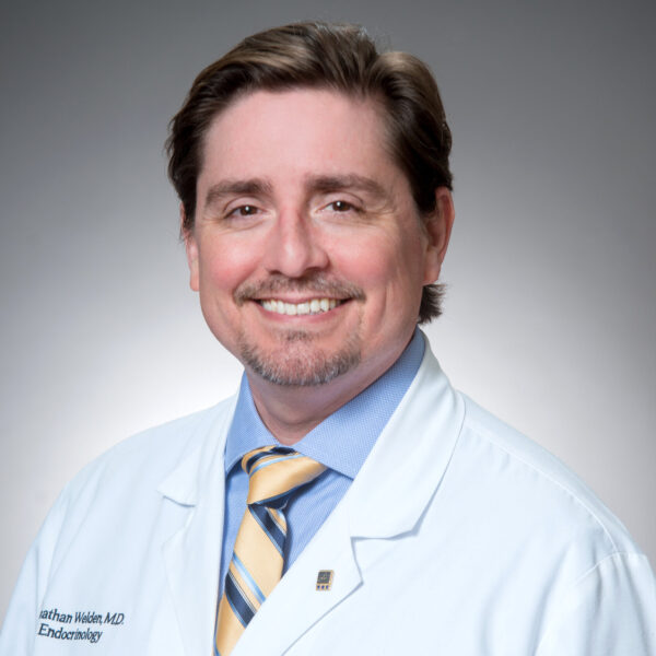 A smiling Jonathan G. Welden in a white lab coat from The Baton Rouge Clinic AMC poses against a plain background.