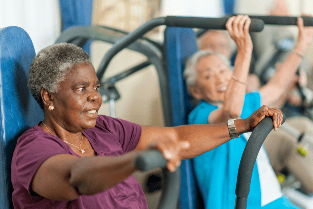 Two elderly women are using exercise machines in a gym. They appear to be engaged in a fitness activity.