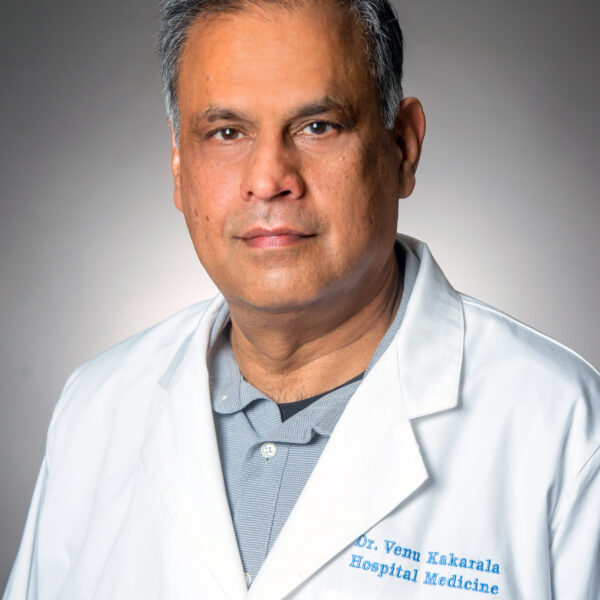 A man in a white lab coat with "Dr. Venu Kakarala Hospital Medicine" embroidered on it, standing against a plain background.